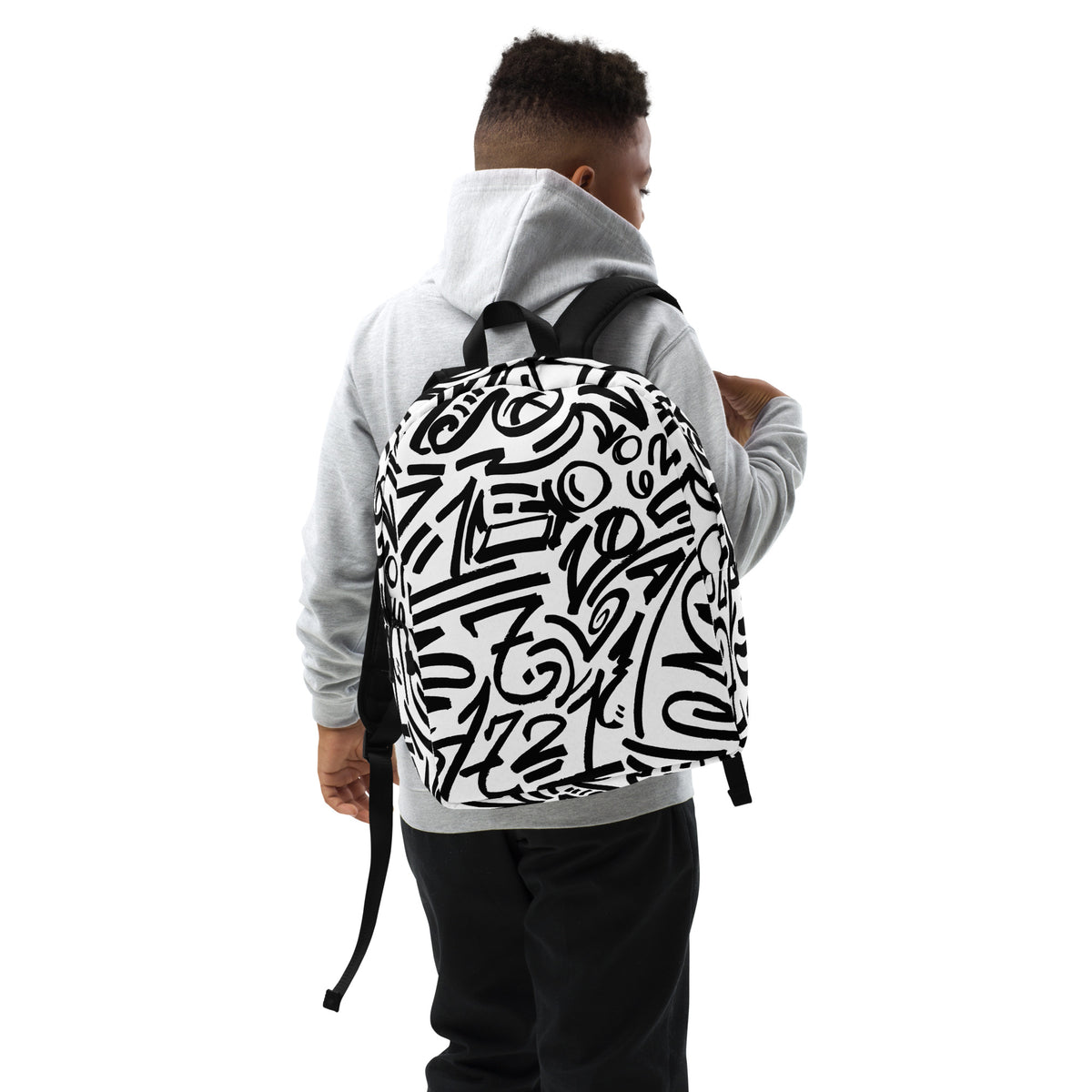 Boy in a grey hoodie wearing the glyph backpack, reaching back for the shoulder strap